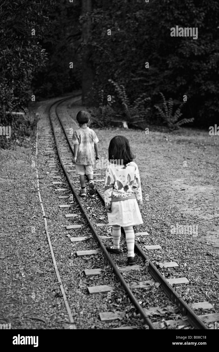 Girl folows boy along miniature railway track in a public park New Zealand Stock Photo