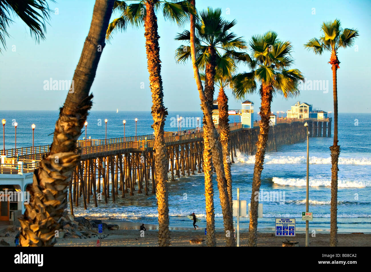 Surfers prepare to enter the Pacific Ocean at the Oceanside Pier in Southern California Stock Photo
