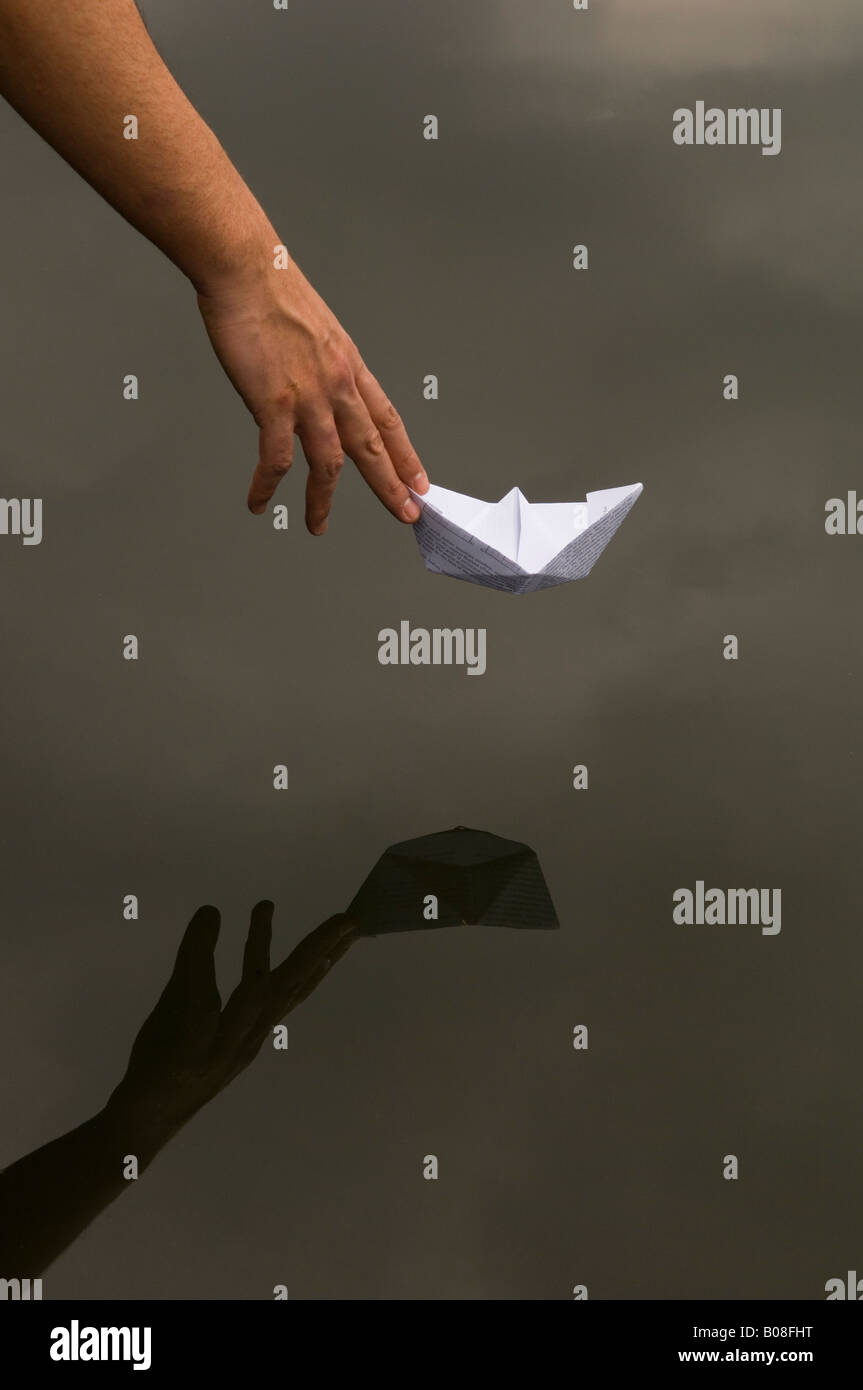 man placing origami boat in water Stock Photo