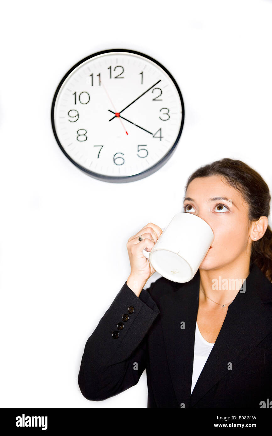 Businesswoman drinking coffee and looking at clock Stock Photo