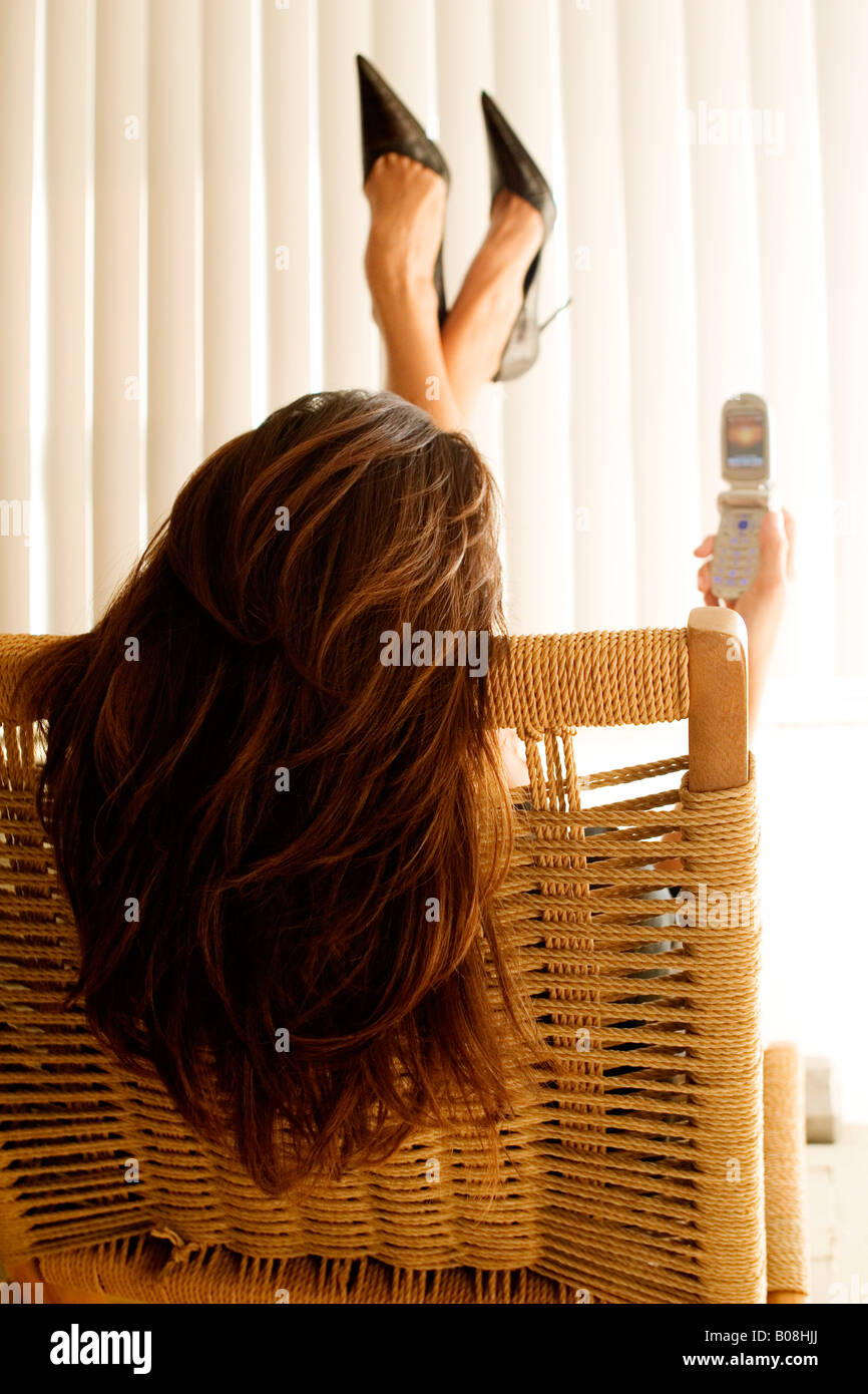 Woman with cell phone kicking feet up in the air Stock Photo Alamy