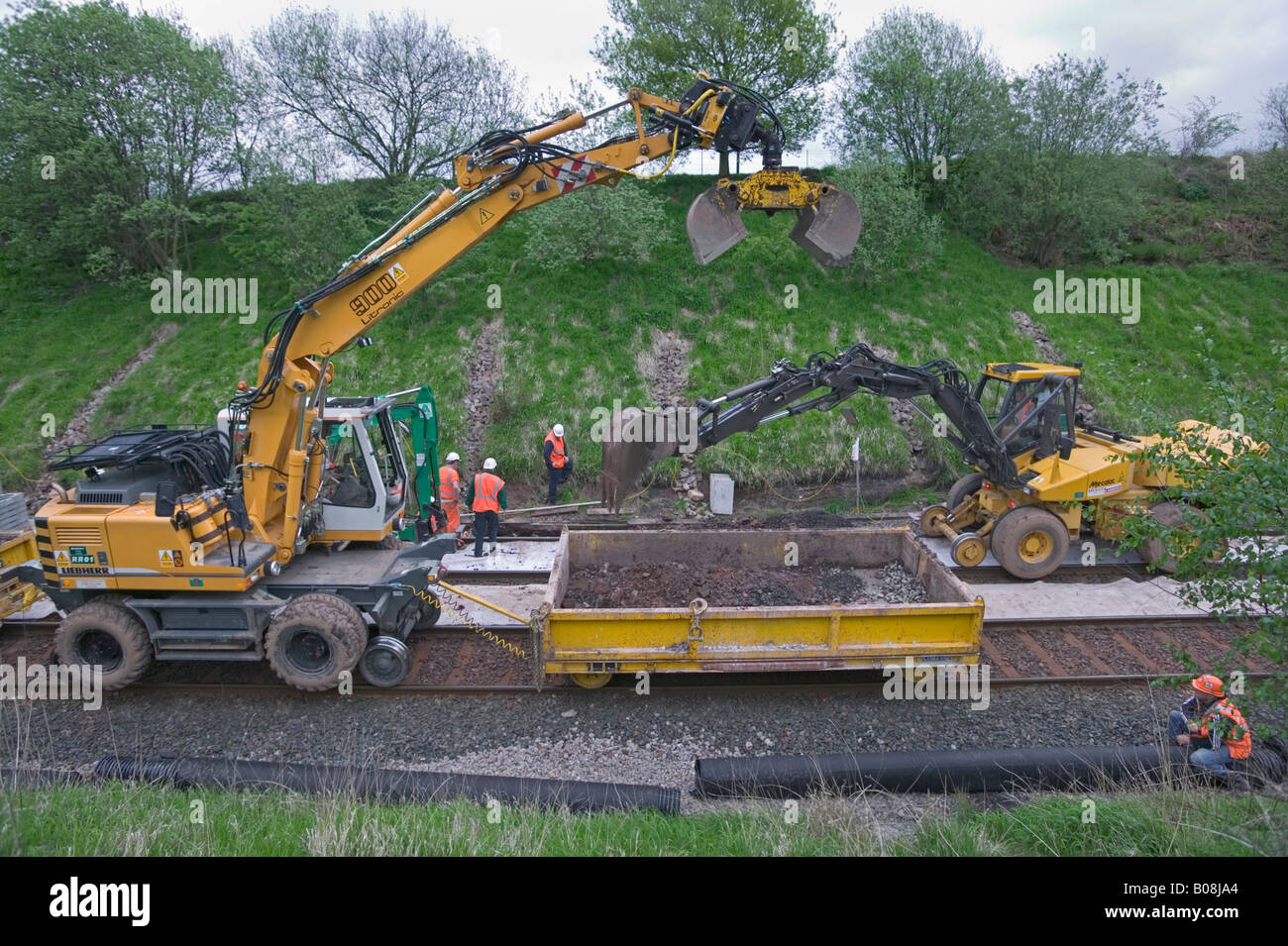 Specialist contractor using road-rail vehicles to excavate and replace outdated track drainage system on a busy rail network. Stock Photo