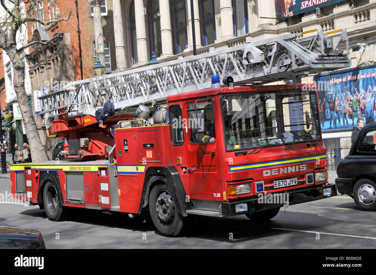 Alexander Dennis turntable ladder red fire engine vehicle front side view driving along road on 999 emergency call West End London England UK Stock Photo