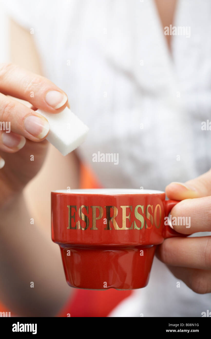 Hand adding cube of sugar into an espresso cup Stock Photo