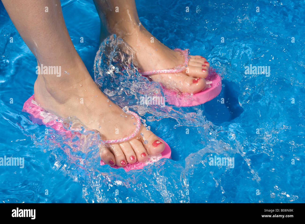 Feet wearing flip-flops in a paddling pool Stock Photo