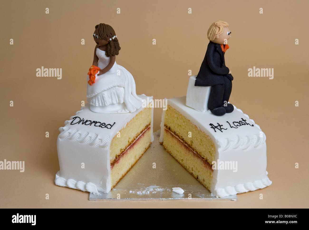 Broken wedding Cake with divorced couple back to back Stock Photo