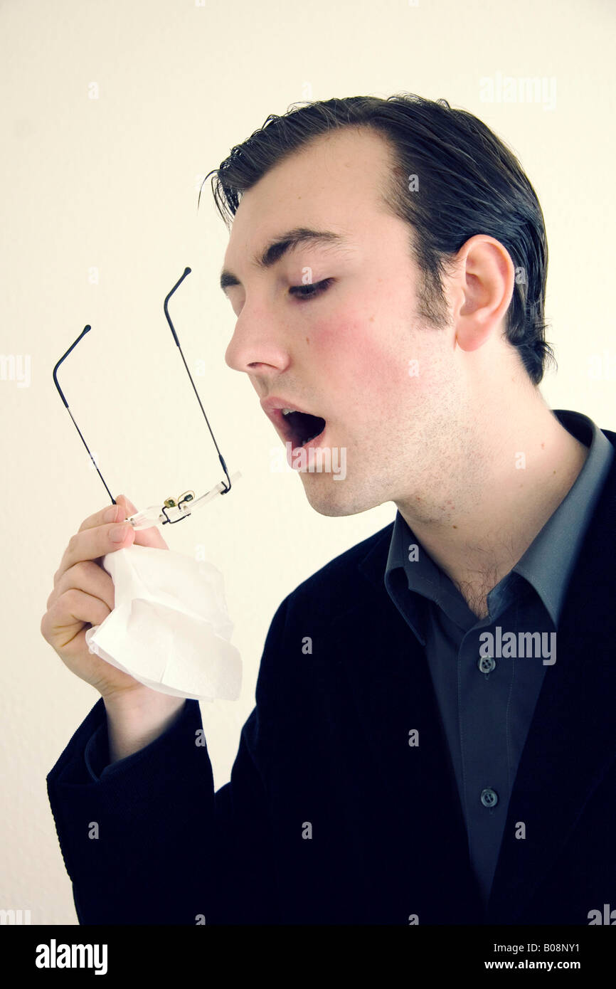 Dandy, young man cleaning his glasses Stock Photo