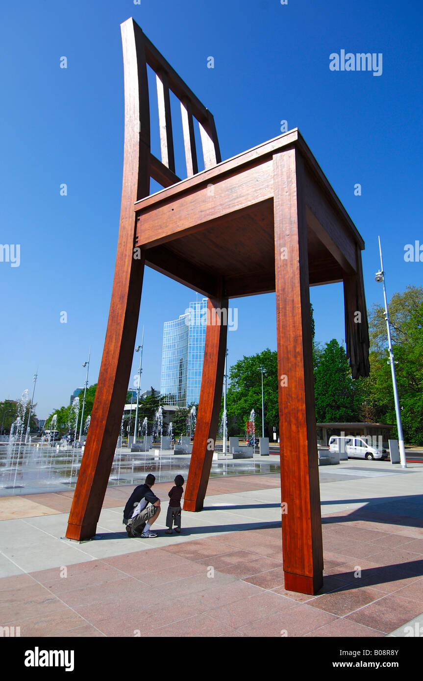Father and son at a memorial for the victims of land mines, 'Broken Chair' by Daniel Berset, Square of Nations, Place des Natio Stock Photo