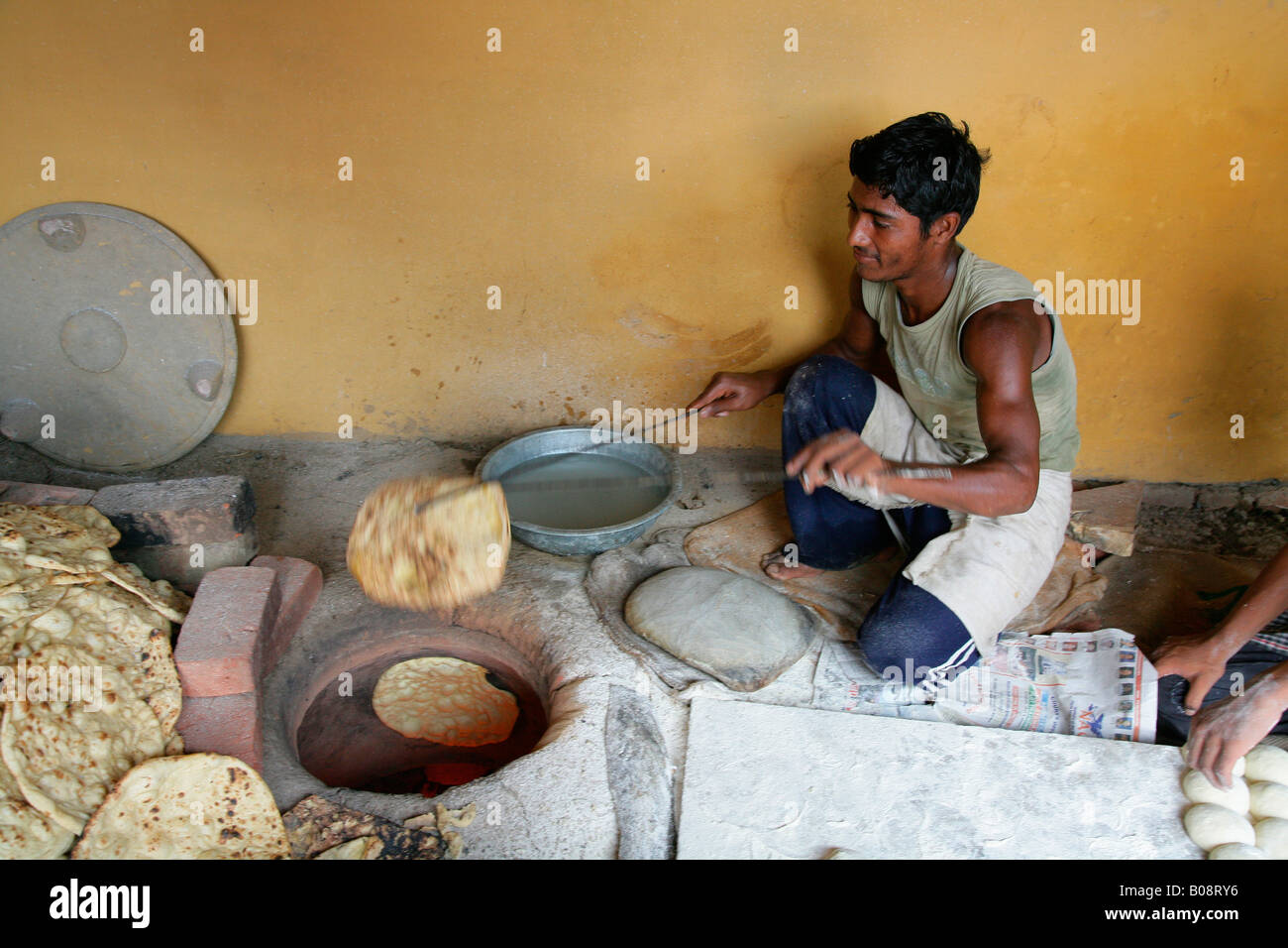 Man taking naan bread out of the oven, Bareilly, Uttar Pradesh, India, Asia Stock Photo