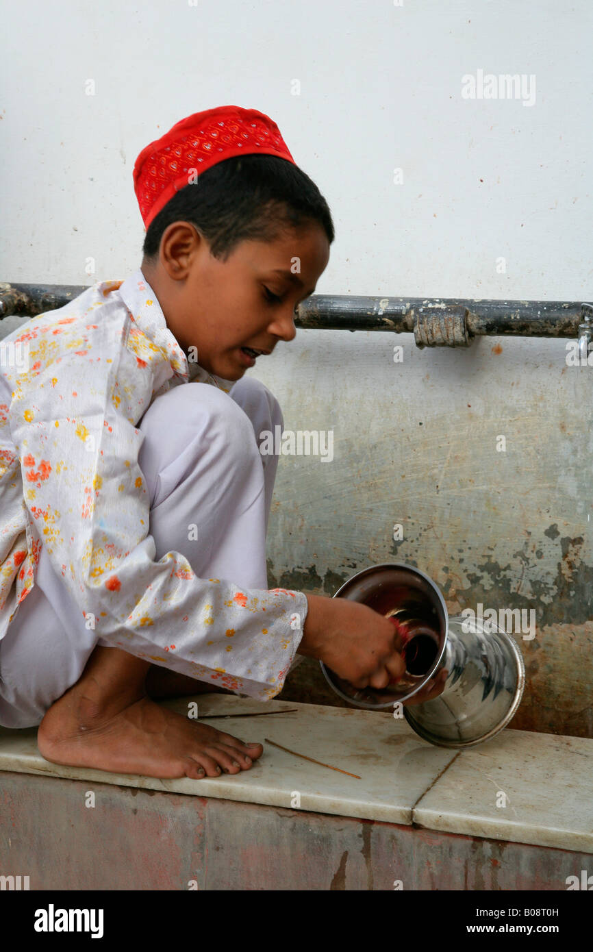 Boy cleaning ritual objects used at a shrine, Bareilly, Uttar Pradesh, India, Asia Stock Photo