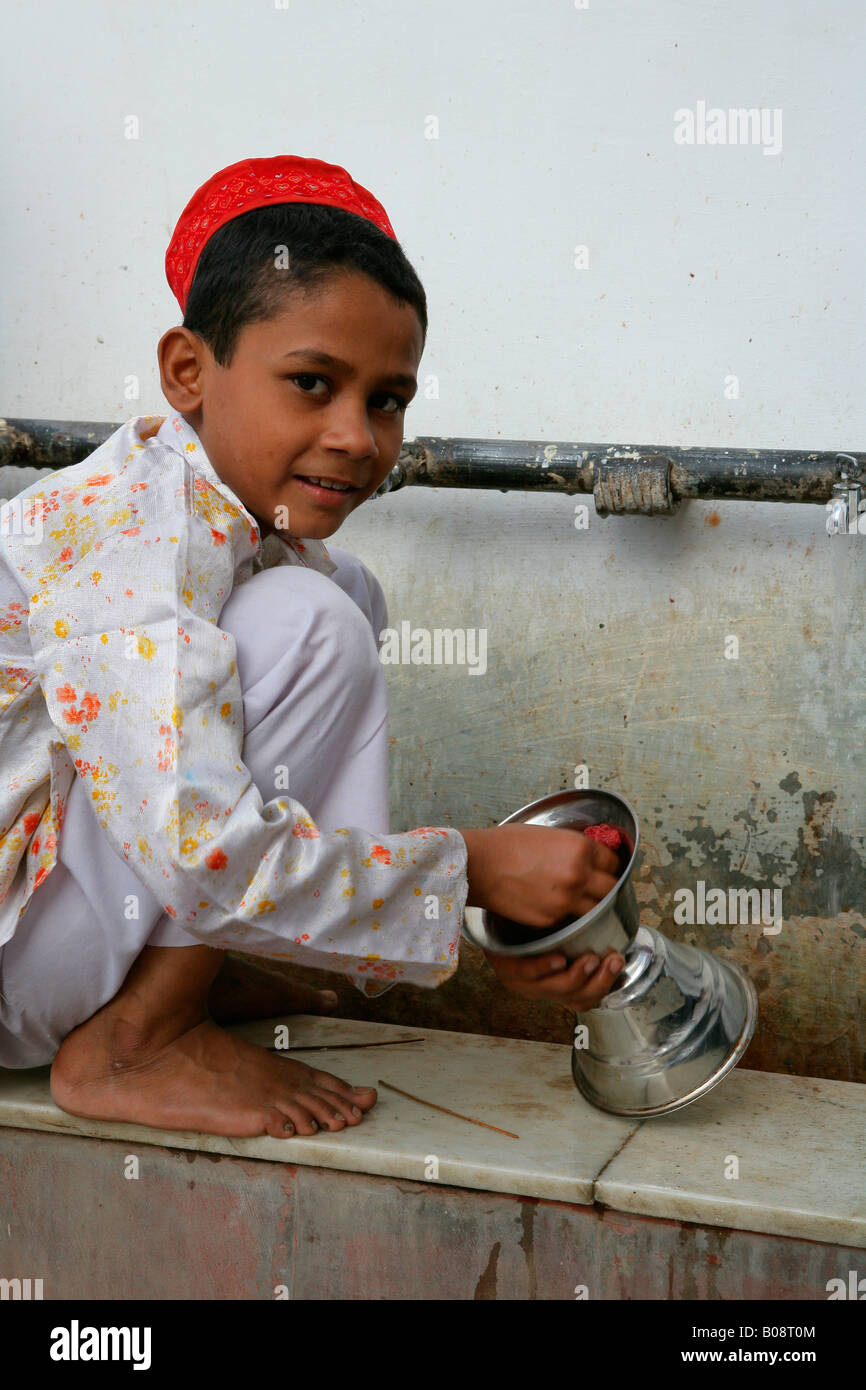 Boy cleaning ritual objects used at a shrine, Bareilly, Uttar Pradesh, India, Asia Stock Photo