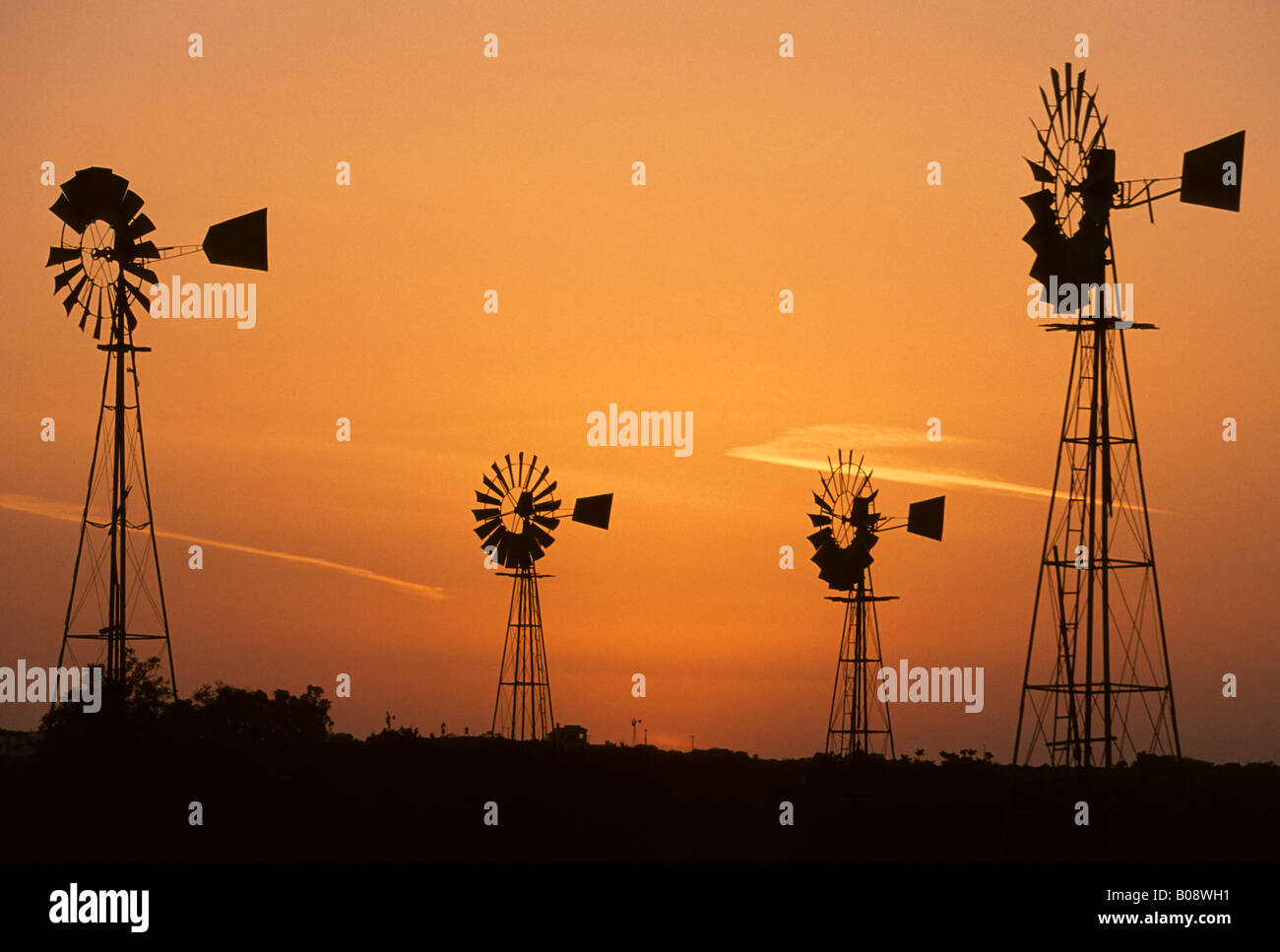 Wind driven water pumps silhouetted against evening sunset sky near Protaras, Cyprus Stock Photo