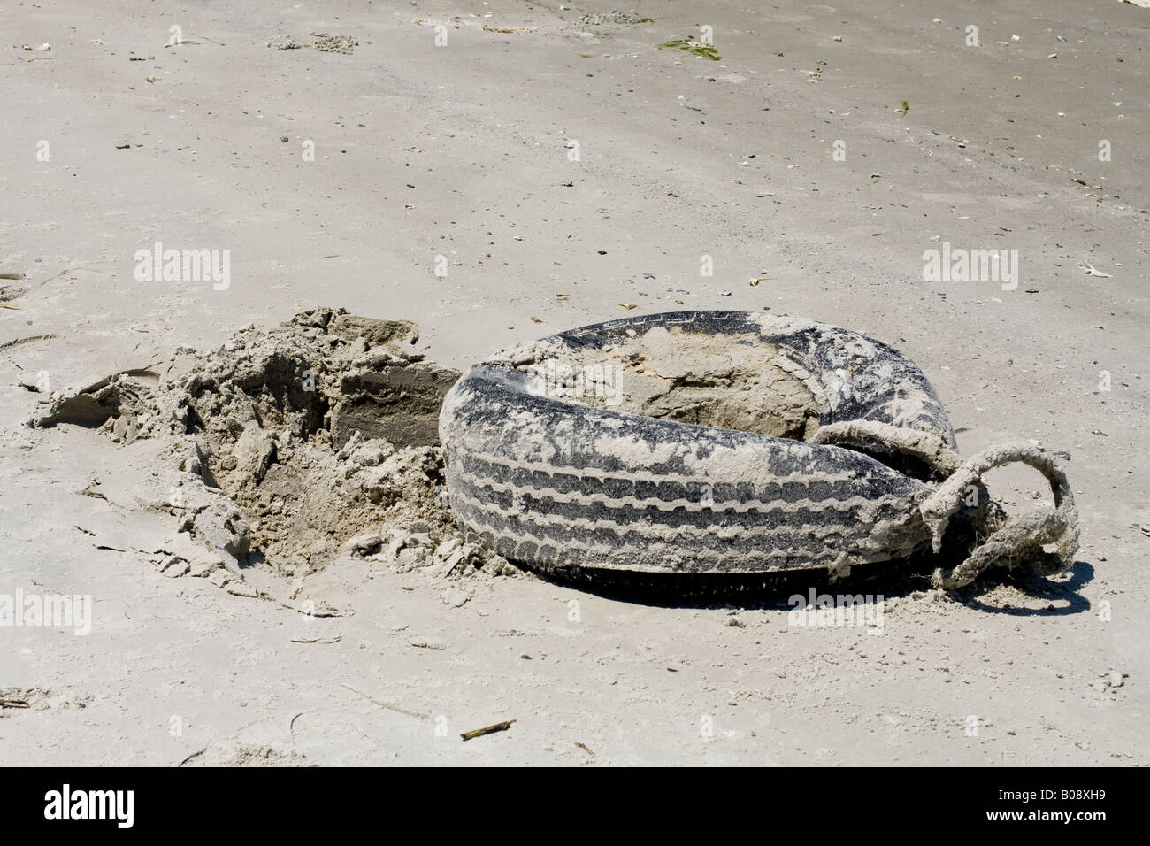 Sand encrusted tire on a white sand beach with a rope tied to it in Mayport Beach, Florida Stock Photo