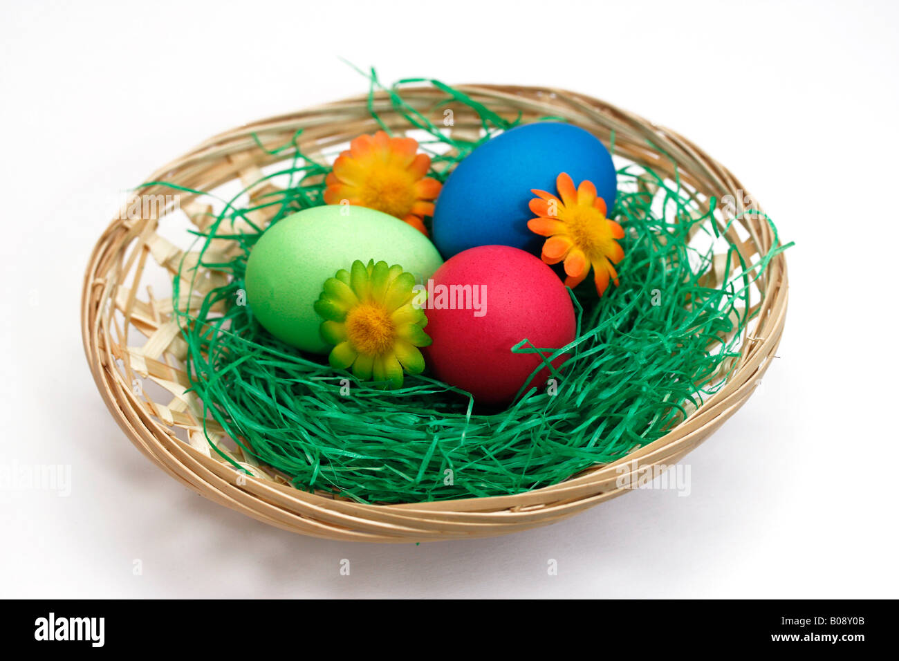Pastel-coloured painted Easter eggs in basket with decorative flowers Stock Photo
