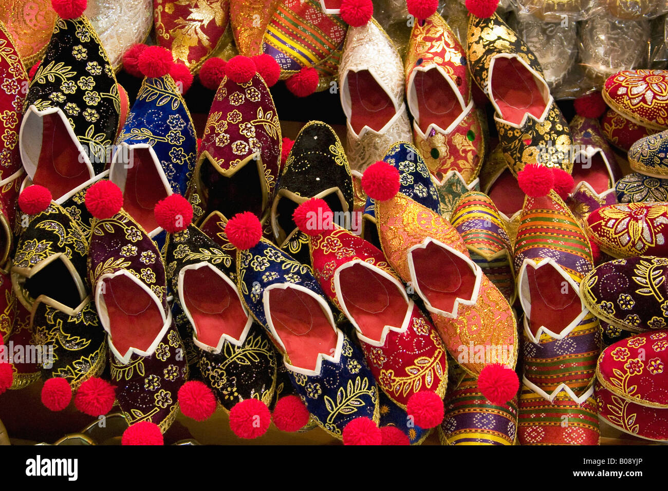 Brightly embroidered oriental shoes with red pom-poms displayed at the Grand Bazaar, Istanbul, Turkey Stock Photo
