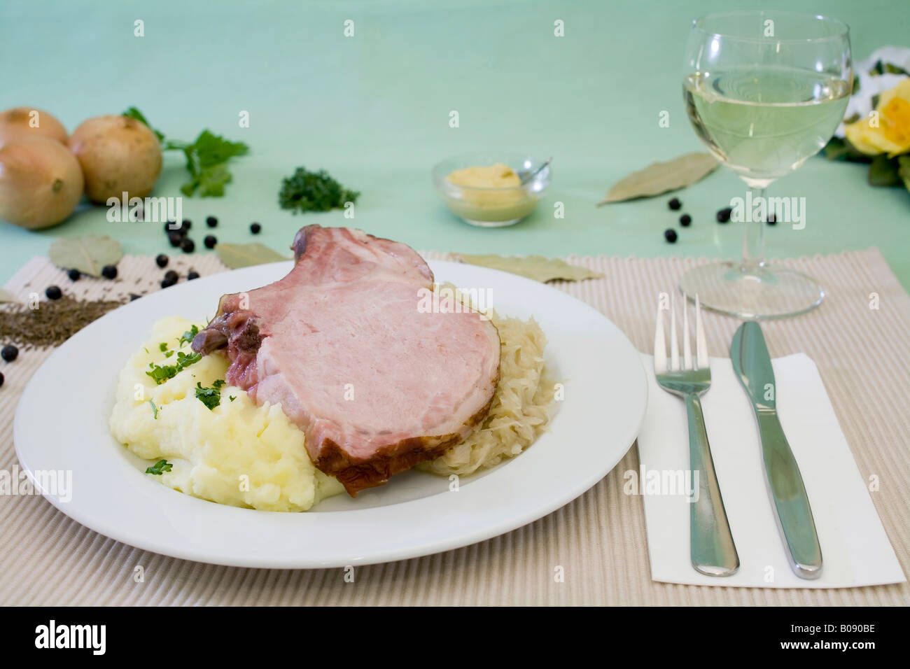 Smoked pork loin with sauerkraut, mashed potatoes and spices served with a glass of white wine Stock Photo