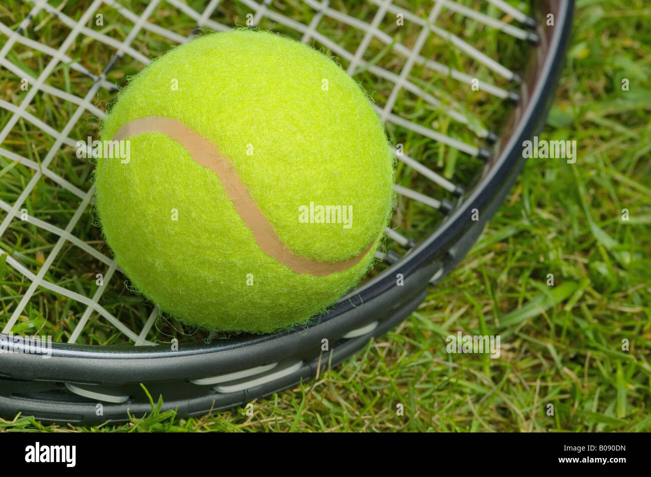 Close up of a tennis ball and racket on grass Stock Photo
