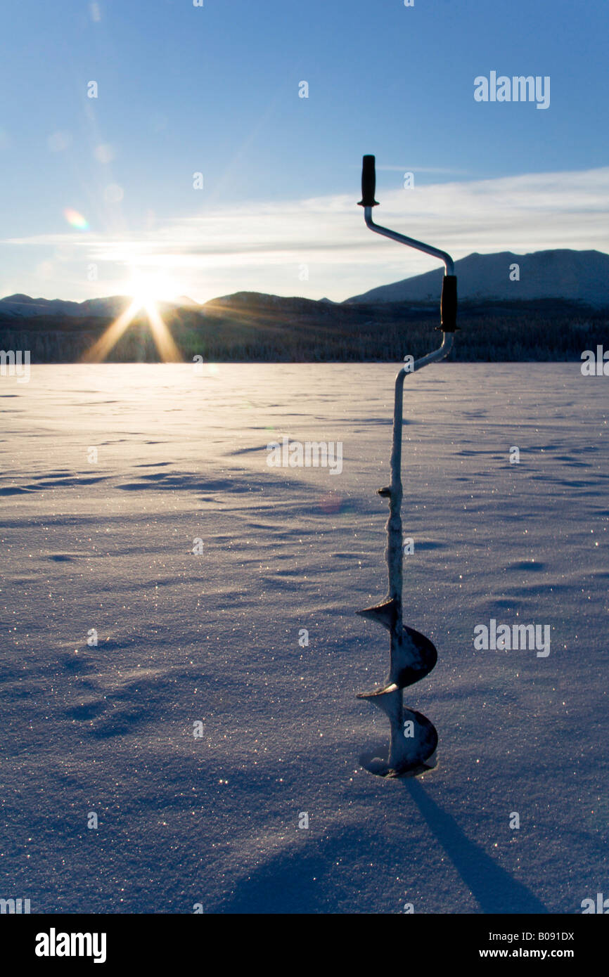 Ice auger used to cut a hole for ice fishing, Fox Lake, Yukon Territory, Canada Stock Photo