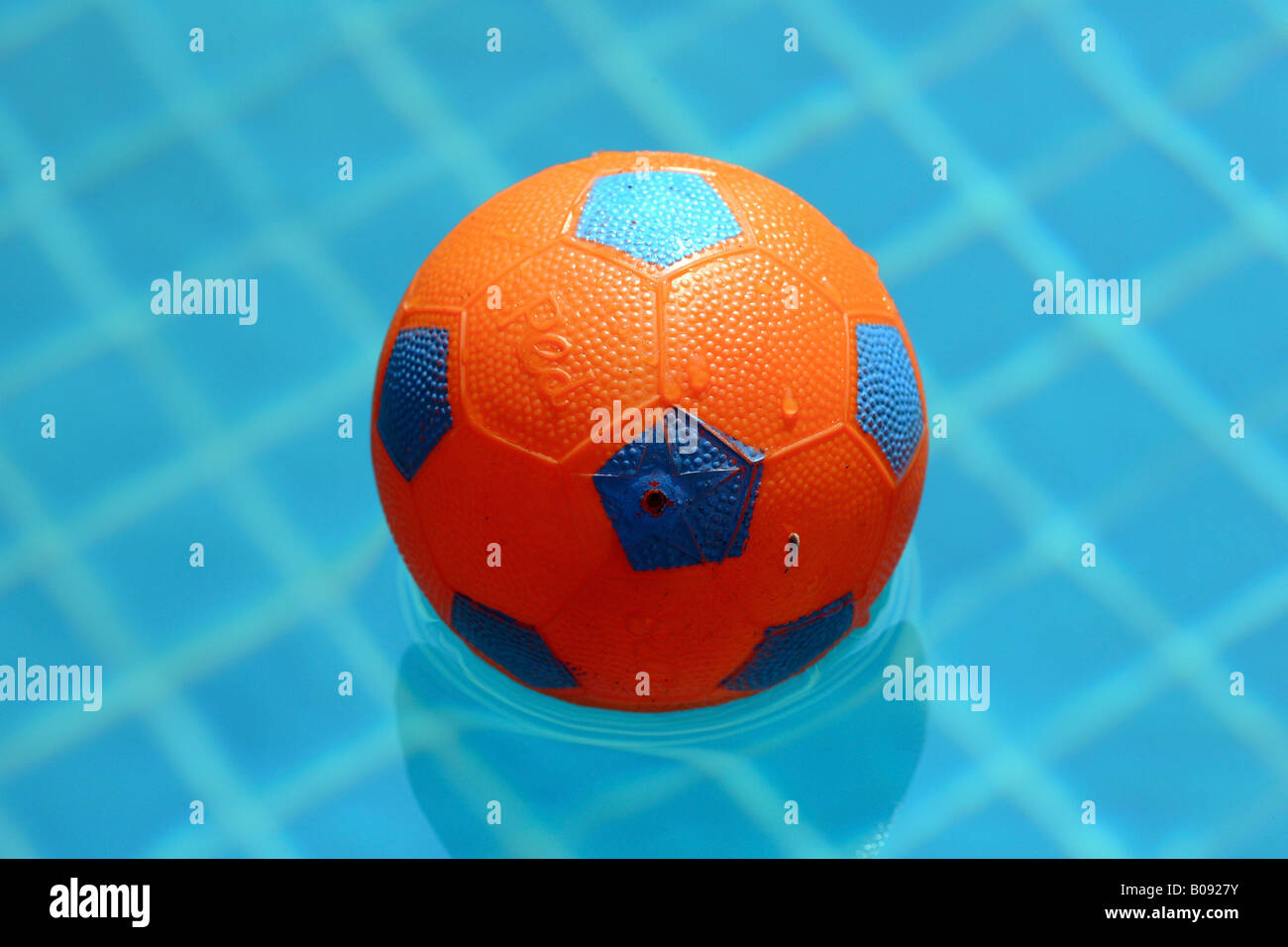 Rubber football floating in a swimming pool Stock Photo