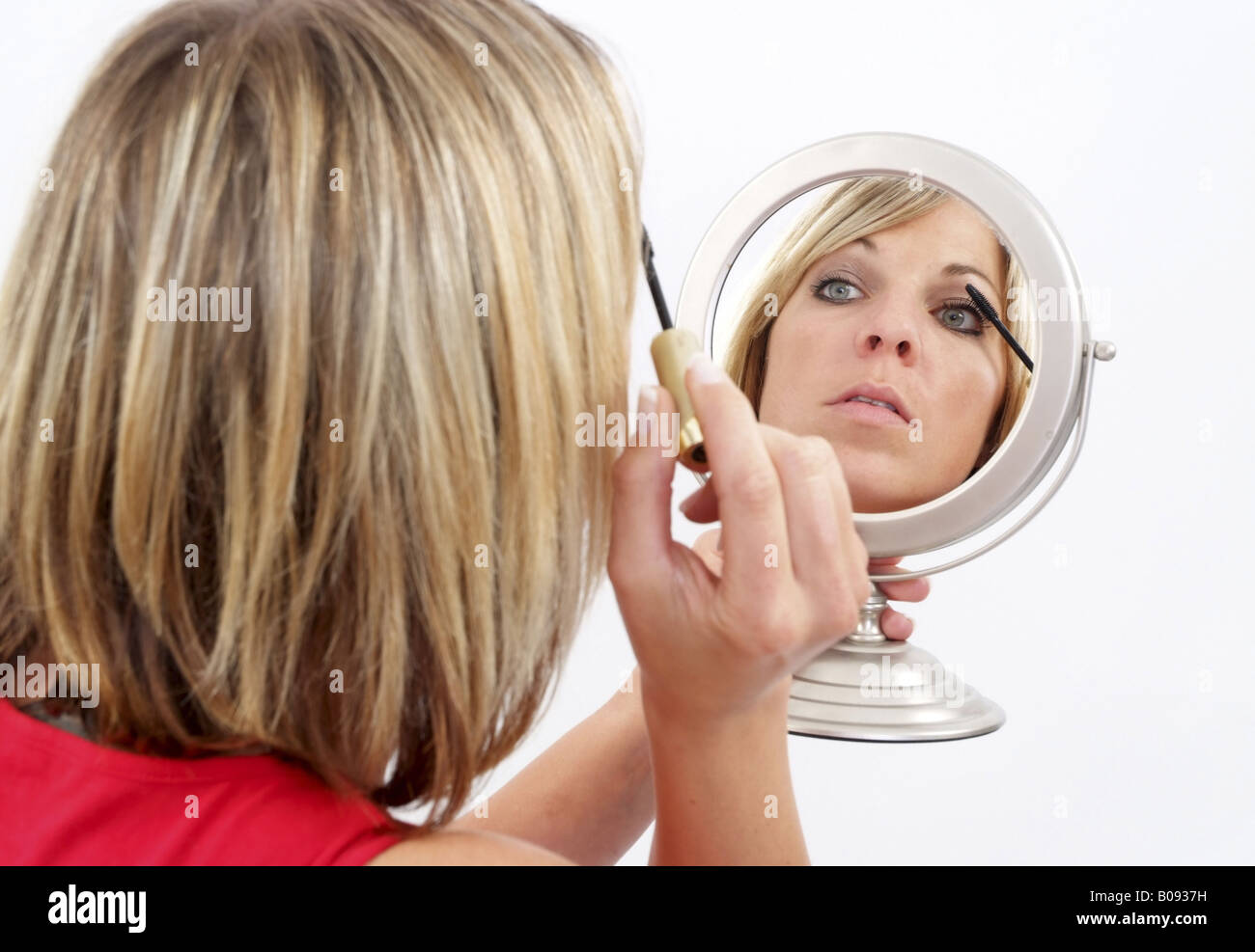 woman with makeup mirror, painting her face Stock Photo