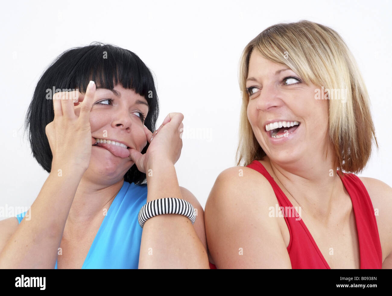two funny girl friends, one blackhaired and one blond woman Stock