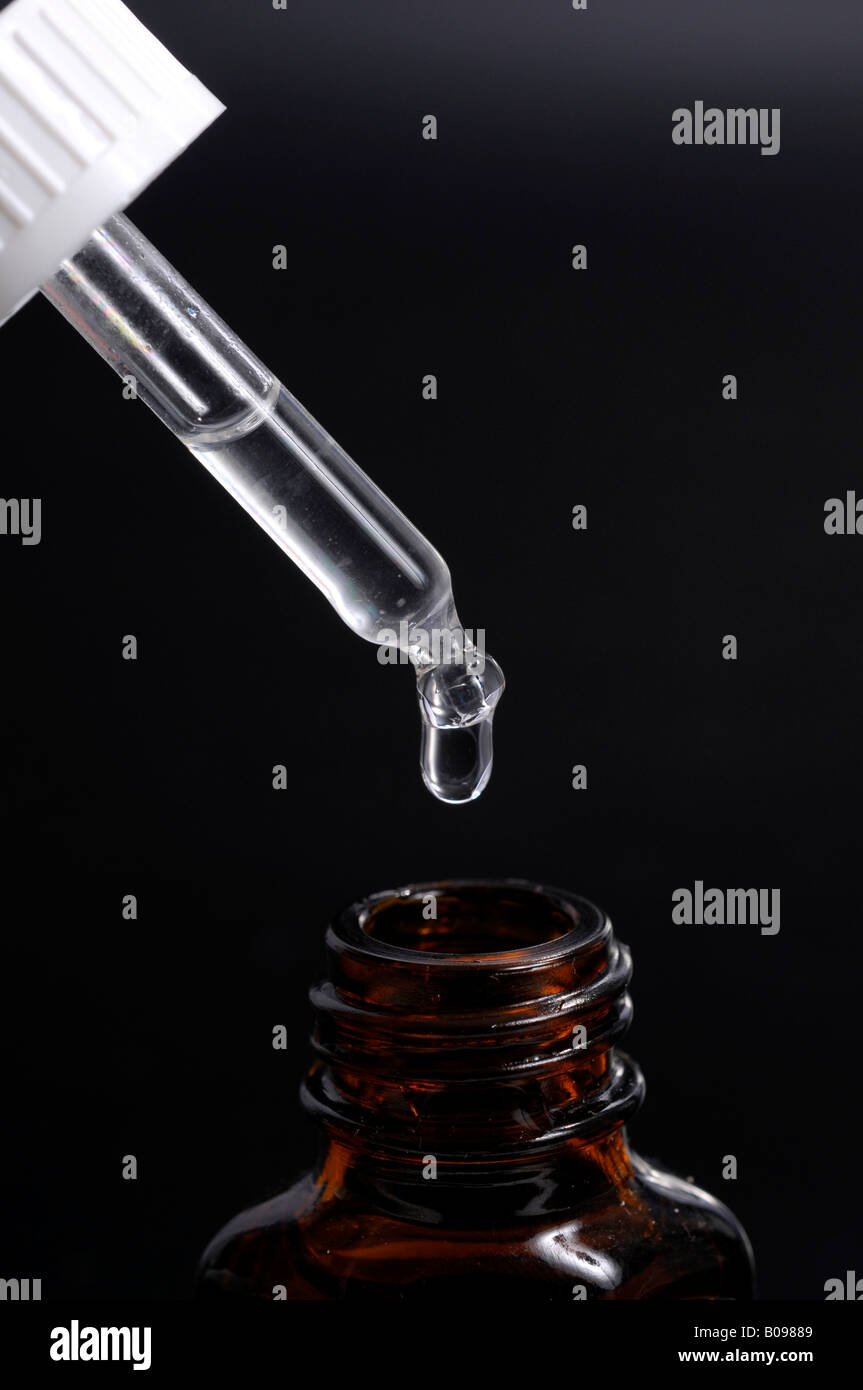 Drop falling from a pipette into a medicine bottle Stock Photo