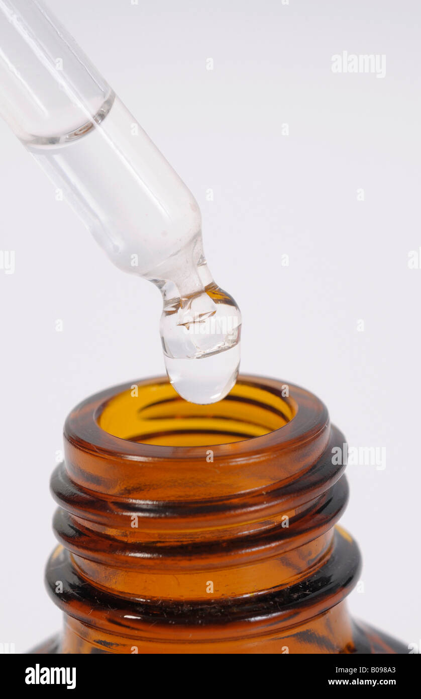 Drop hanging from a pipette or dropper over a medicine bottle Stock