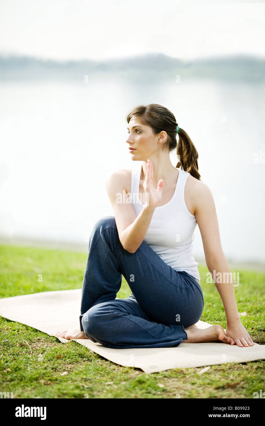 A young woman is practicing yoga in a park near a lake Stock Photo - Alamy