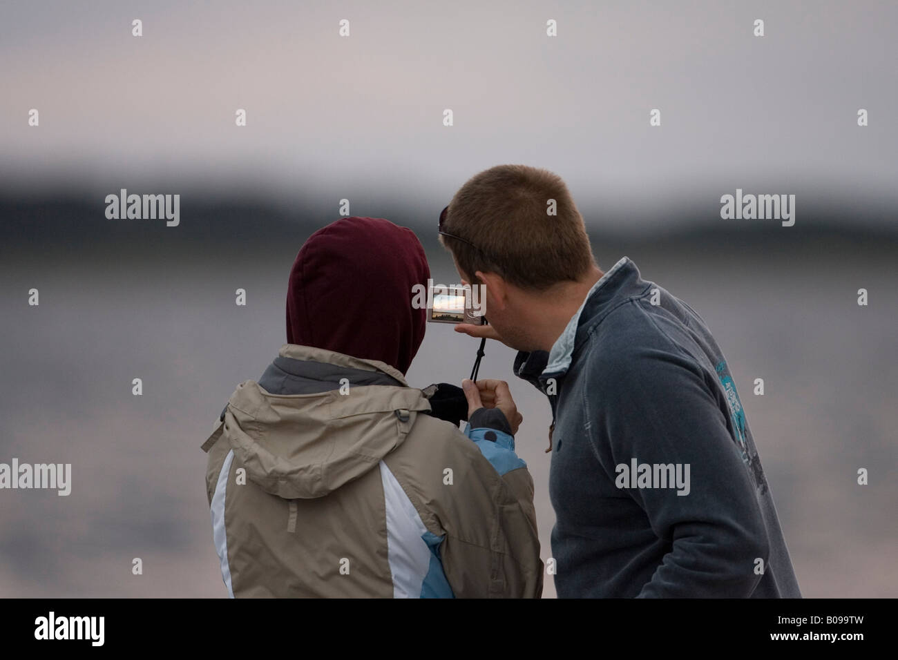 Couple taking photo in twilight with digital camera, Chanonry Point, Scotland, UK Stock Photo