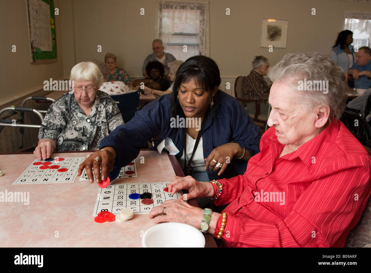 A volunteer works with seniors at a senior center as they play Bingo