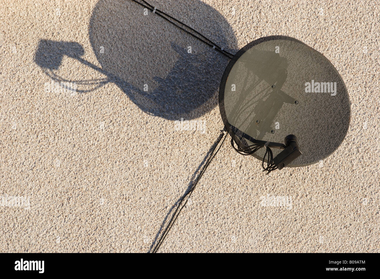 A satellite dish receiver fixed to a plain wall. Stock Photo