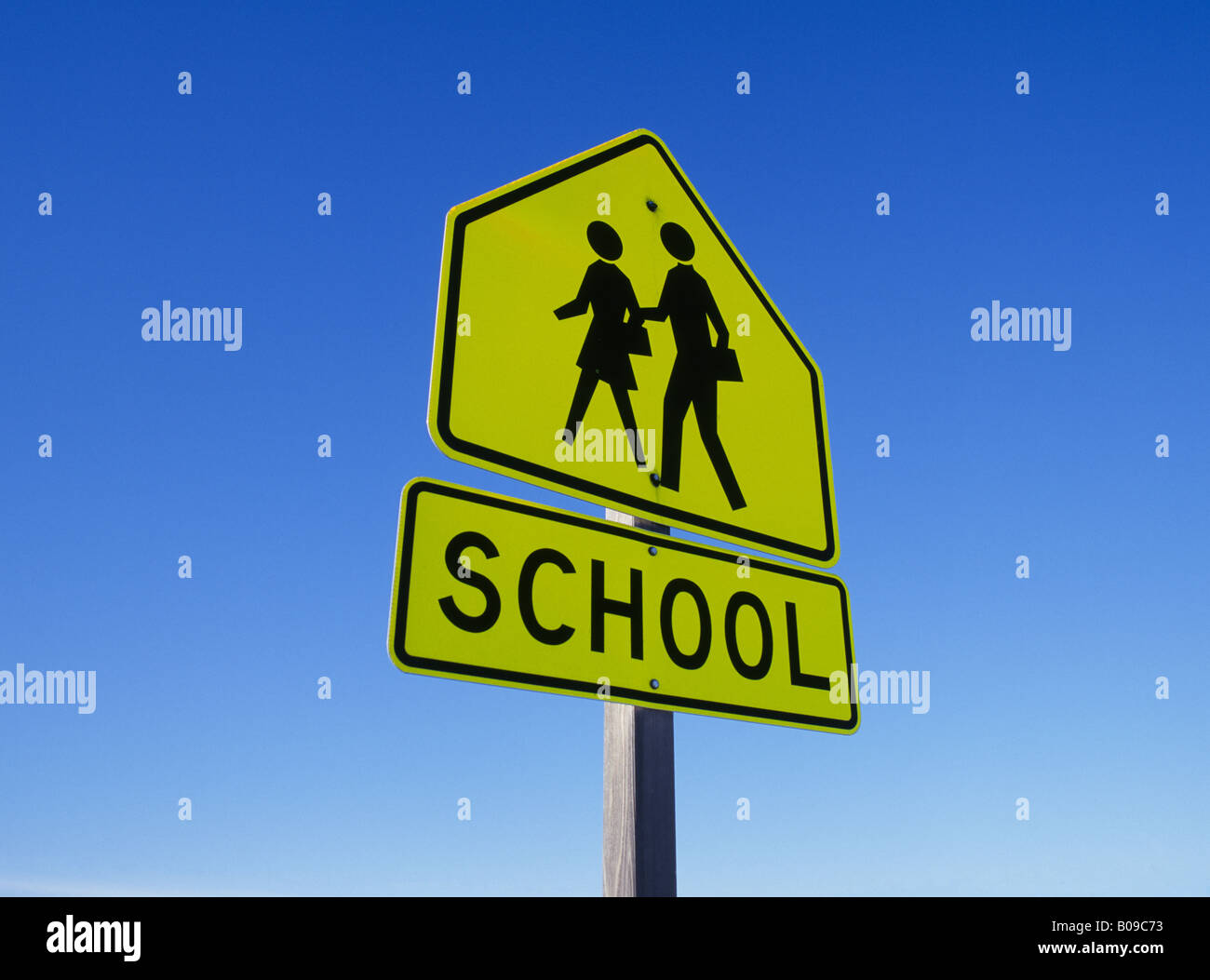 A school sign on a highway warns visitors to stop and yield to children crossing the road Stock Photo