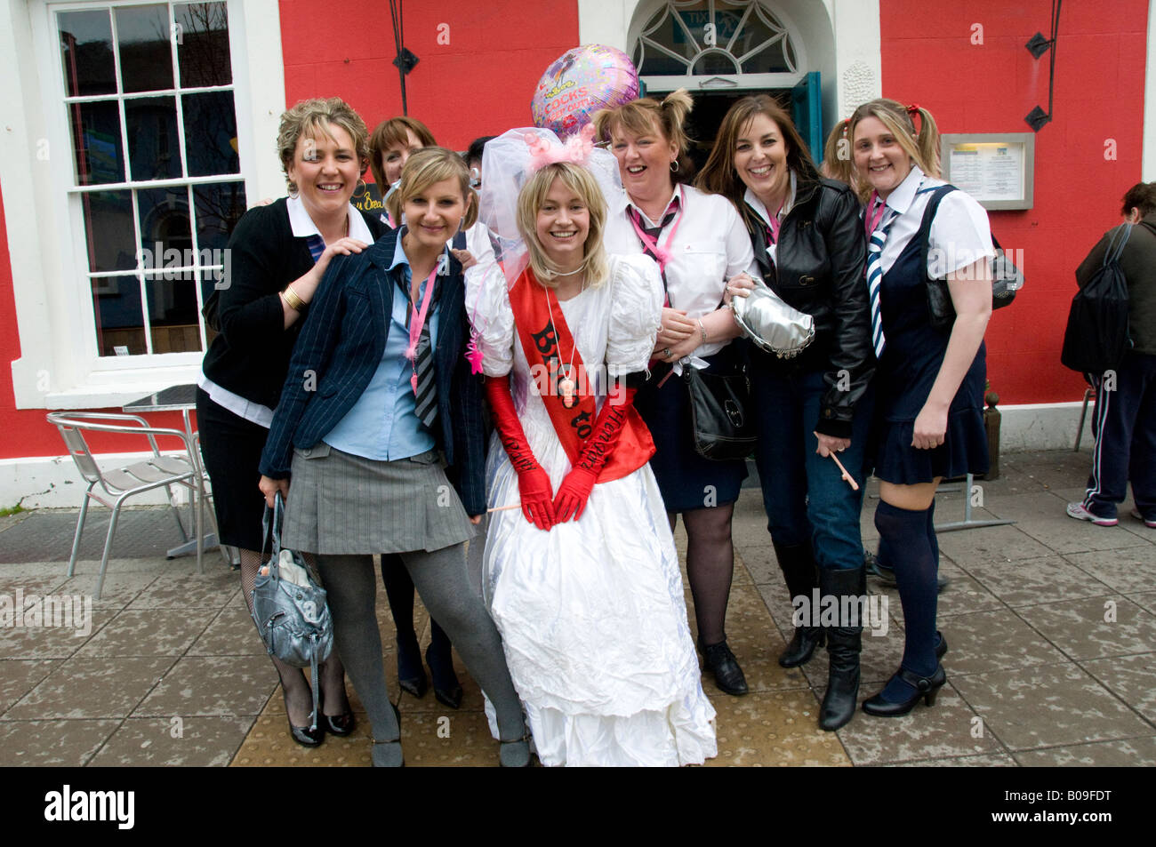 bride to be in wedding dress and girl friends in schoolgirl uniform on hen night Aberaeron Wales UK Stock Photo
