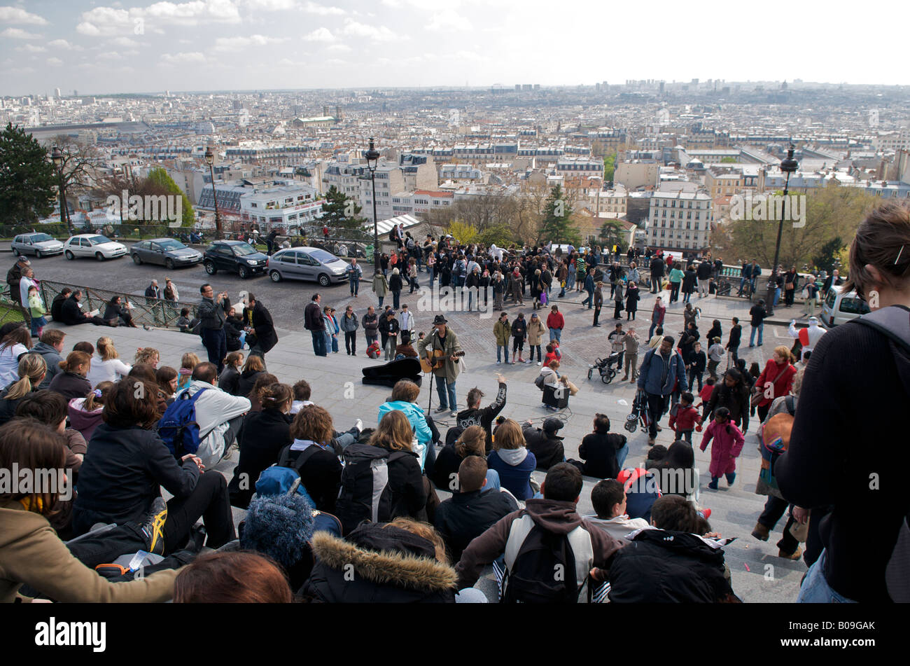 Tourists sitting on the steps of the Basilica of Sacre Coeur overlooking Paris Stock Photo
