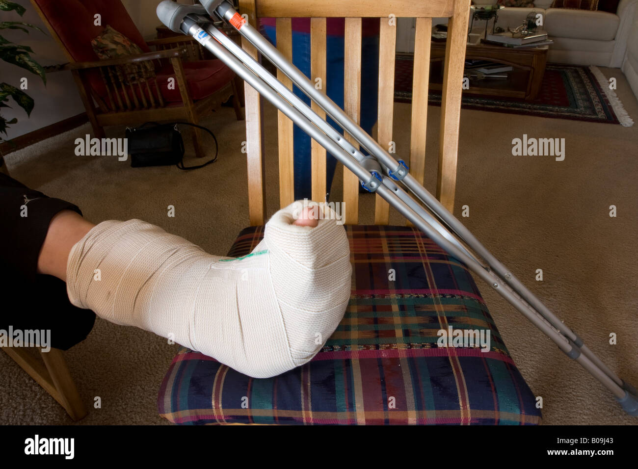 You can see a young man's foot resting on a chair. A medical cast is on
