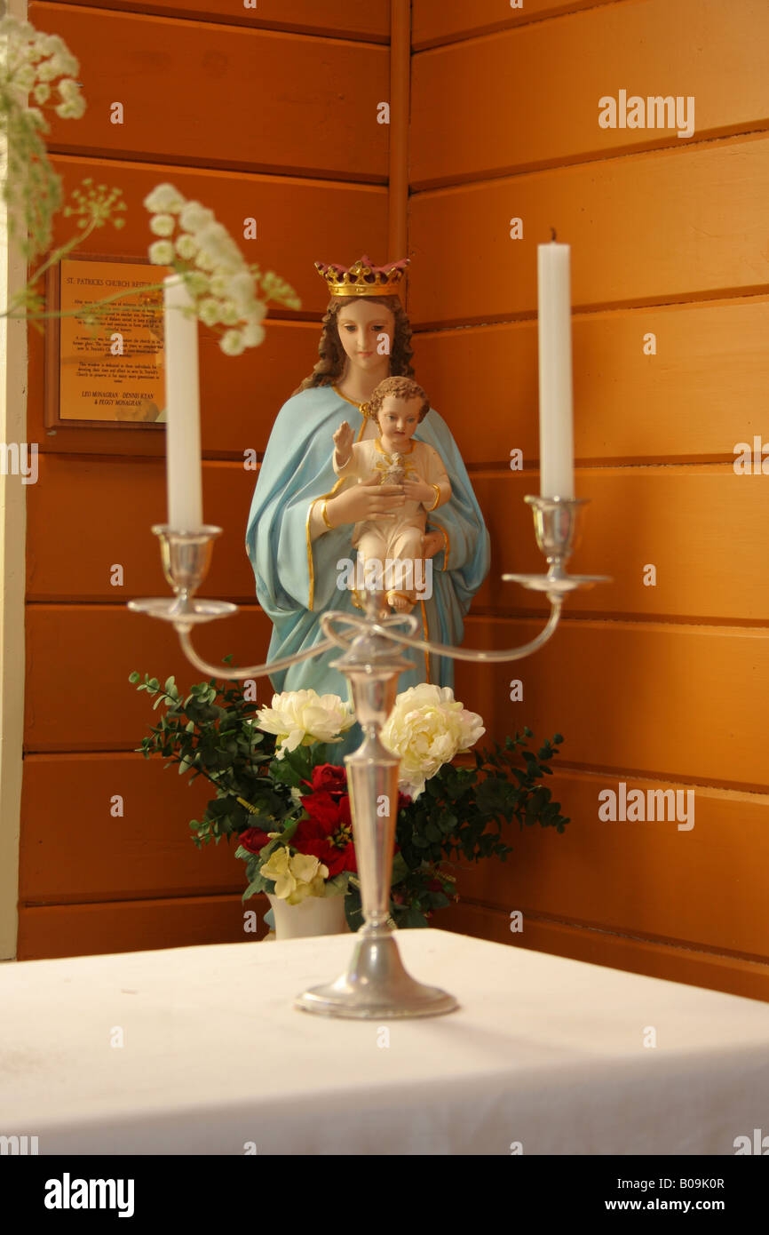 Statue of virgin Mary with baby Jesus behind candle stand in a church. Stock Photo