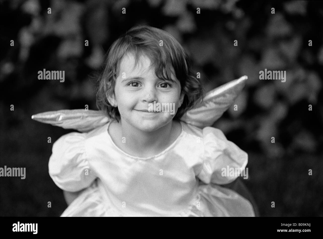 A young girl with angel wings and princess dress smiles for her portrait Stock Photo