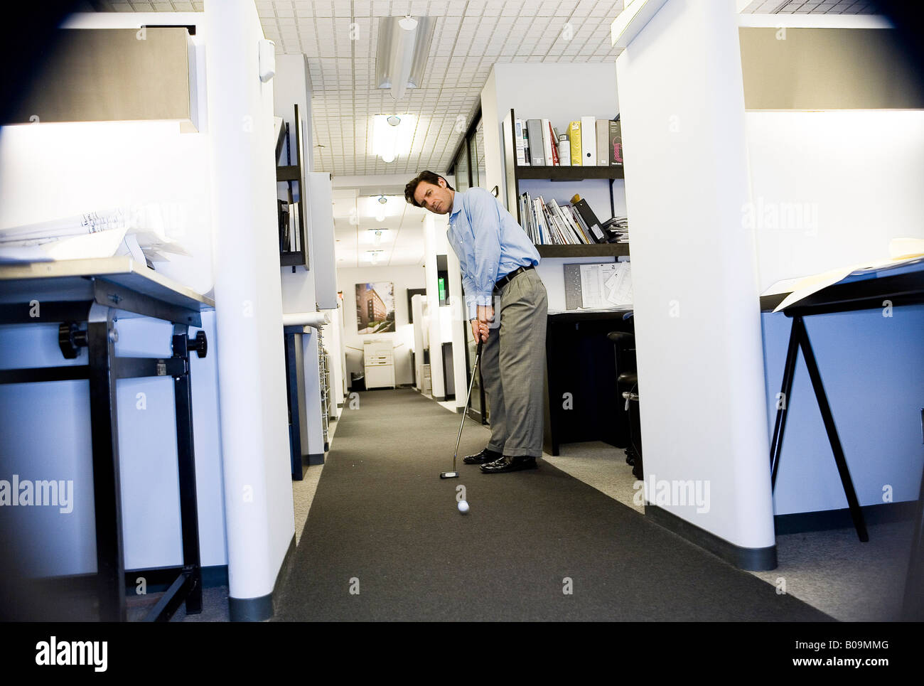 Businessman playing golf in office Stock Photo