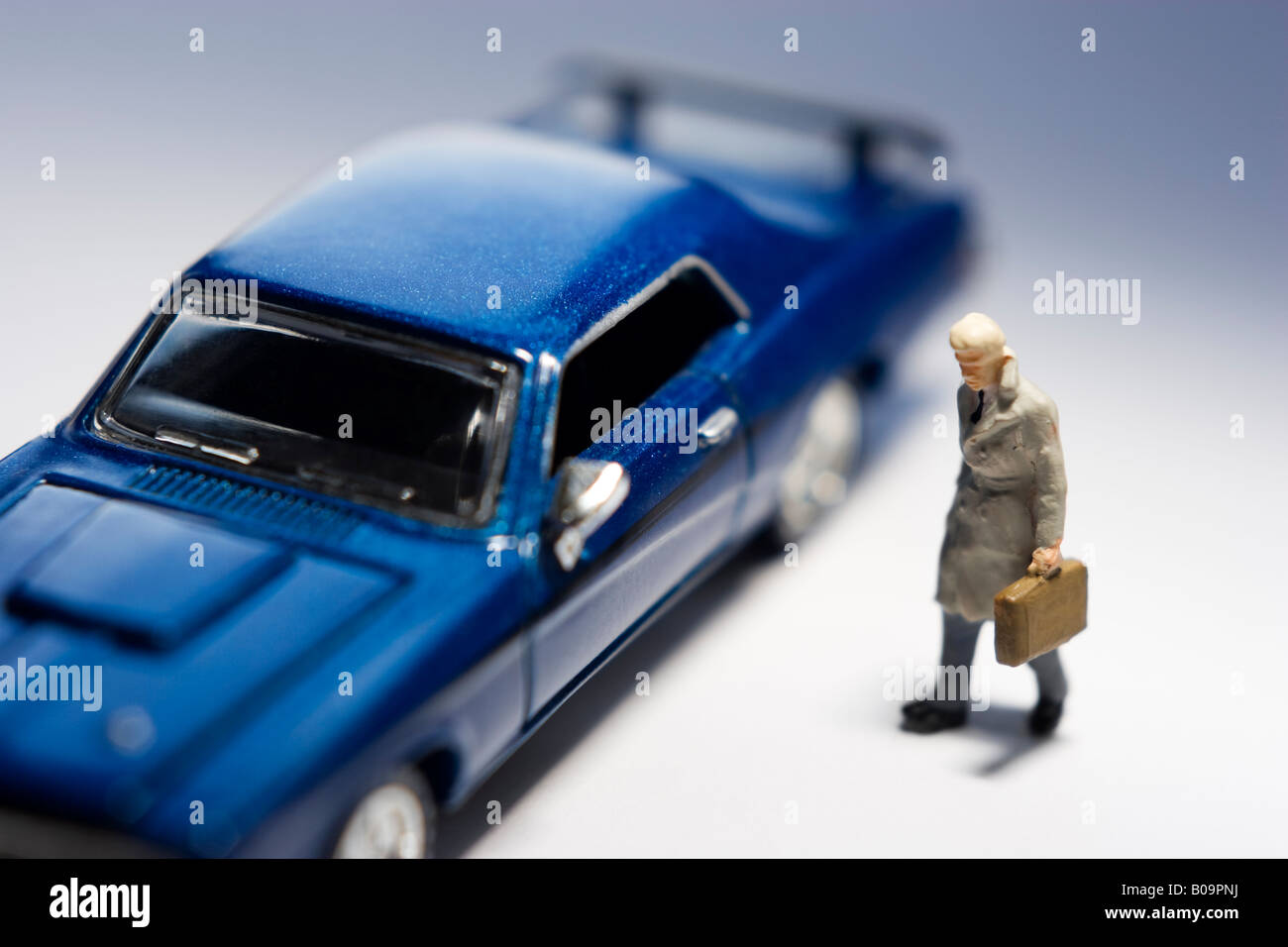 Businessman figurine looking at blue car Stock Photo