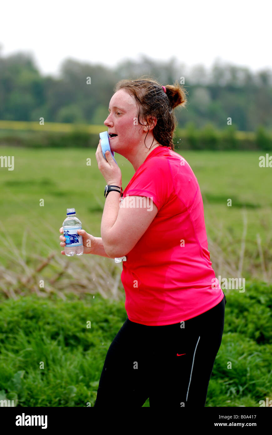 Woman runner in race sponging face, UK Stock Photo Alamy