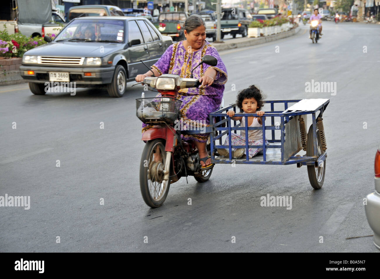 Thai woman on a motorbike with child in the sidecar, Thailand, Sukhothai Stock Photo