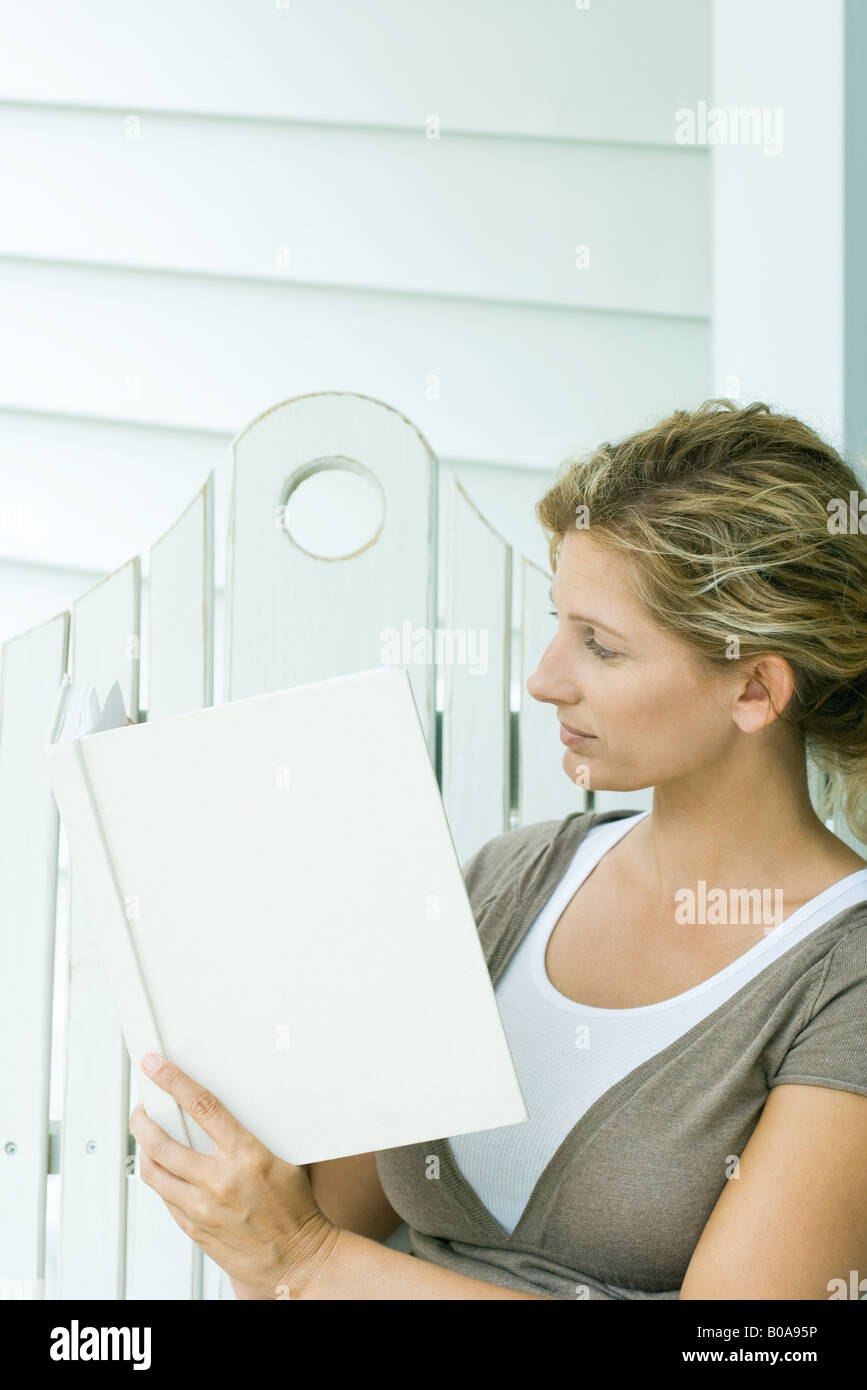 Woman sitting on bench, reading book, side view Stock Photo