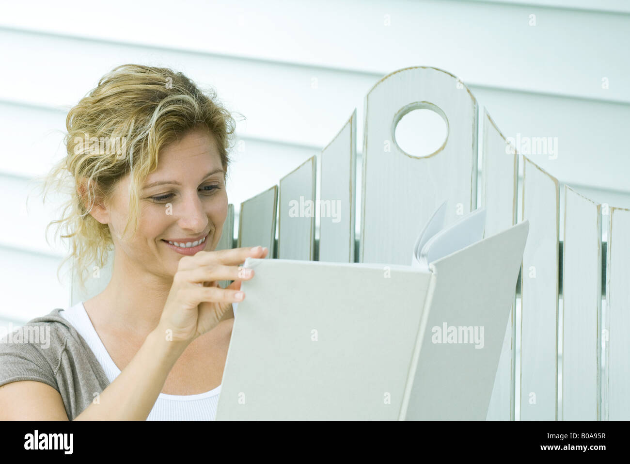 Woman on bench reading book, smiling, close-up Stock Photo
