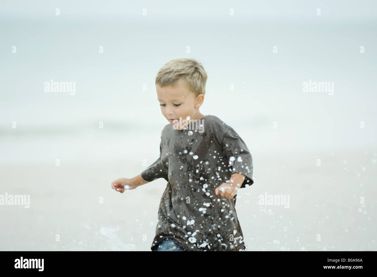 Little boy splashing water at the beach, looking down Stock Photo - Alamy