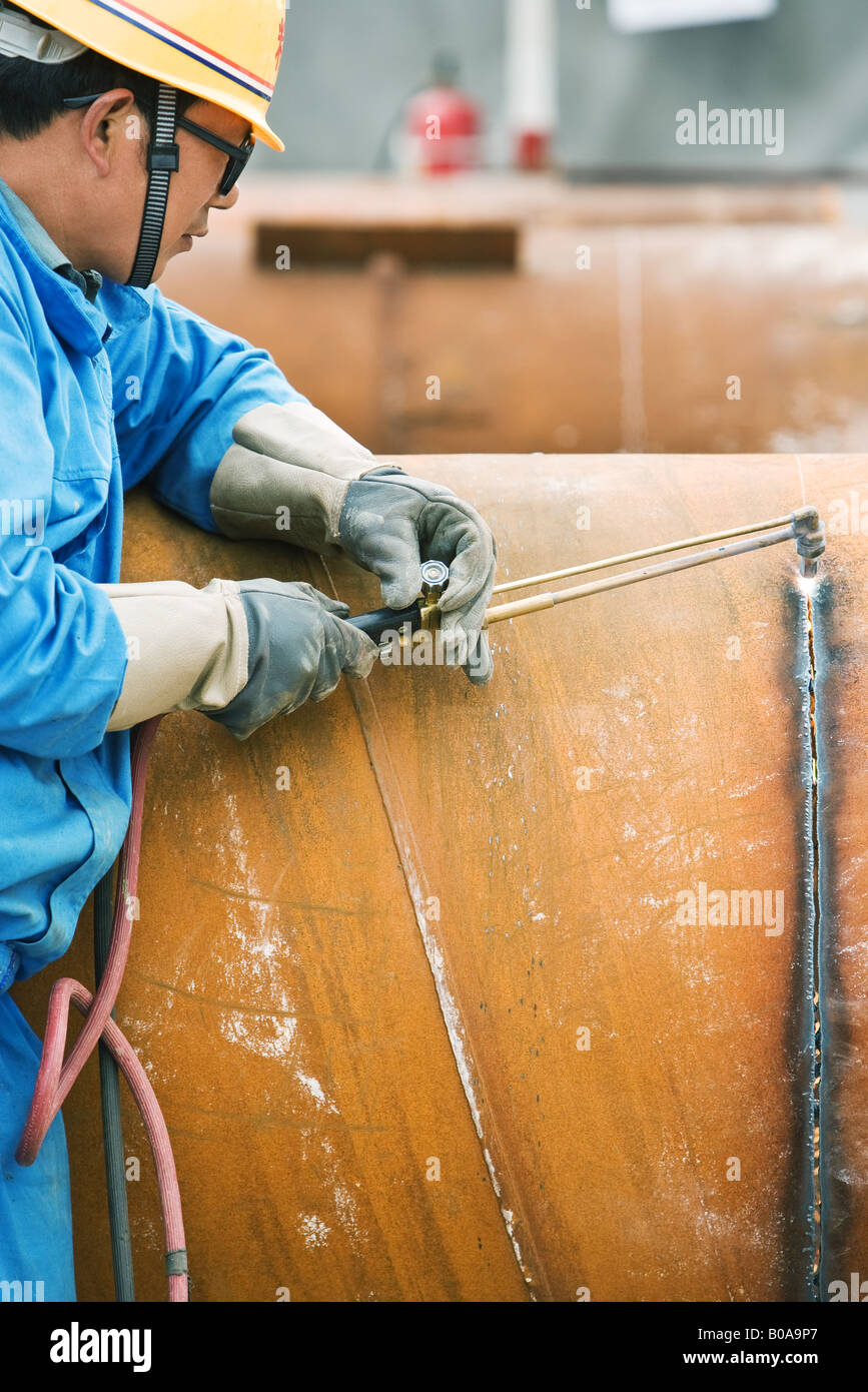 Man cutting metal with welding torch, side view, cropped Stock Photo