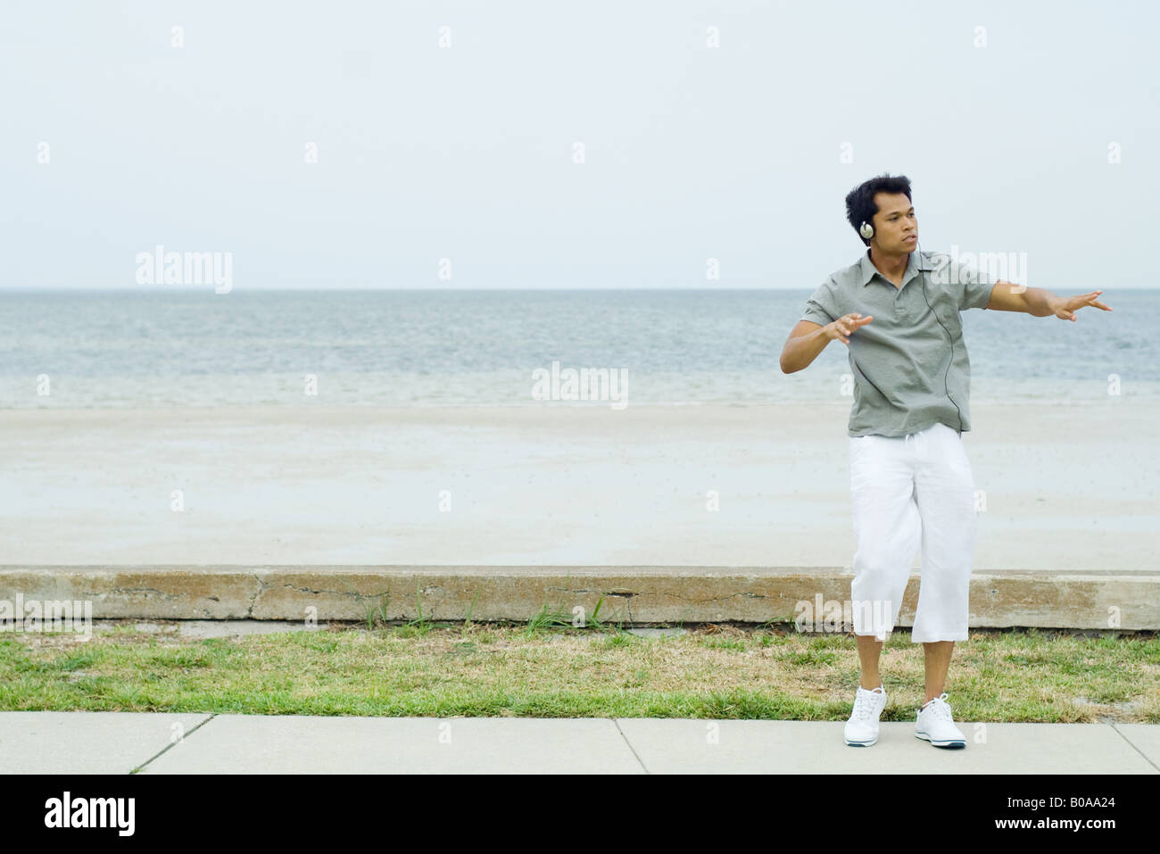 Man listening to headphones at the beach, dancing, looking away Stock Photo