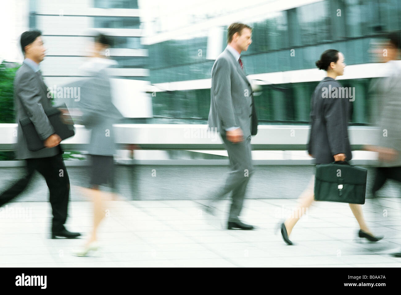 Male and female professionals walking on sidewalk, blurred motion Stock ...