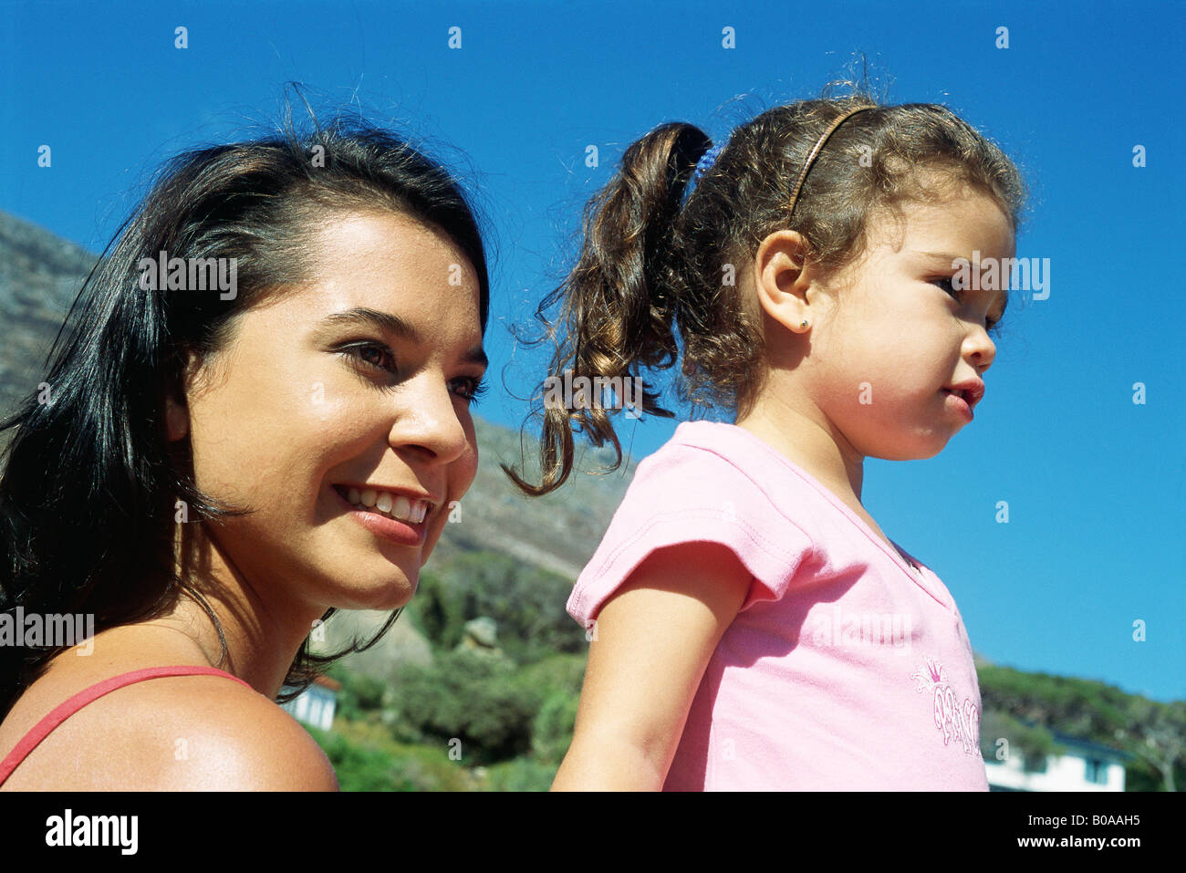 Mother and daughter outdoors, looking away, smiling Stock Photo