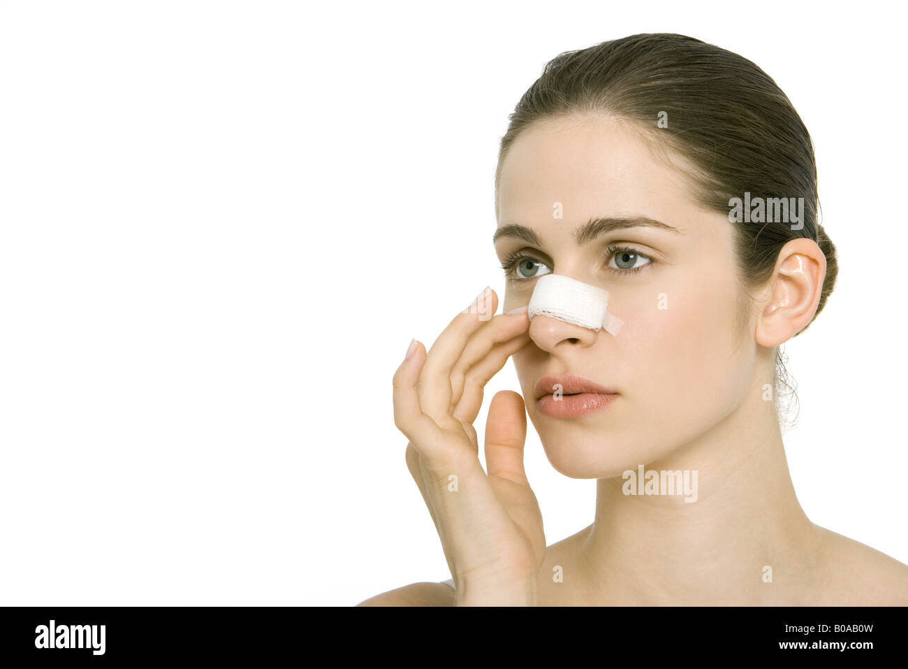 Young woman with bandage on nose, looking away Stock Photo
