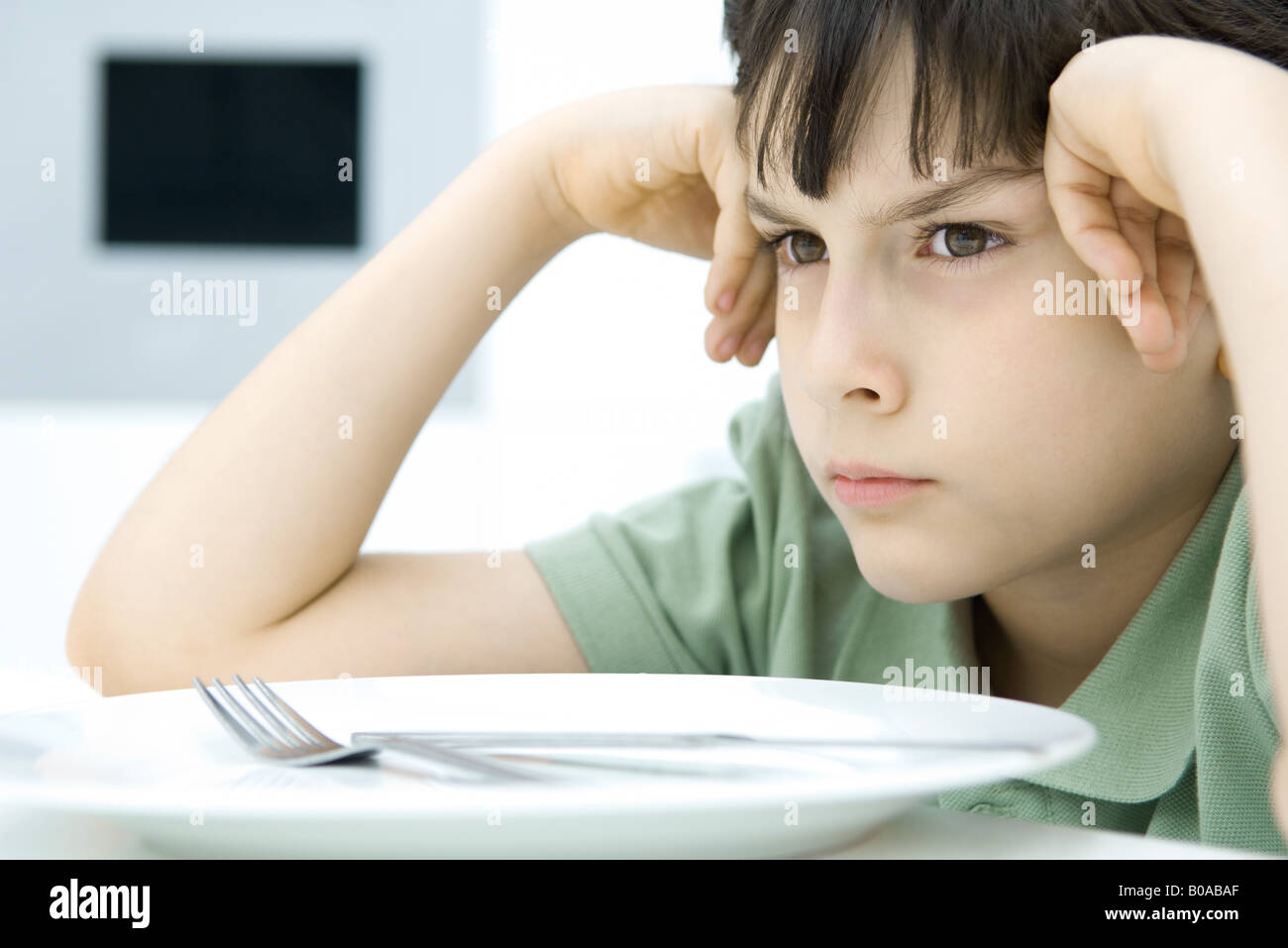 Boy sulking at dinner table, close-up Stock Photo